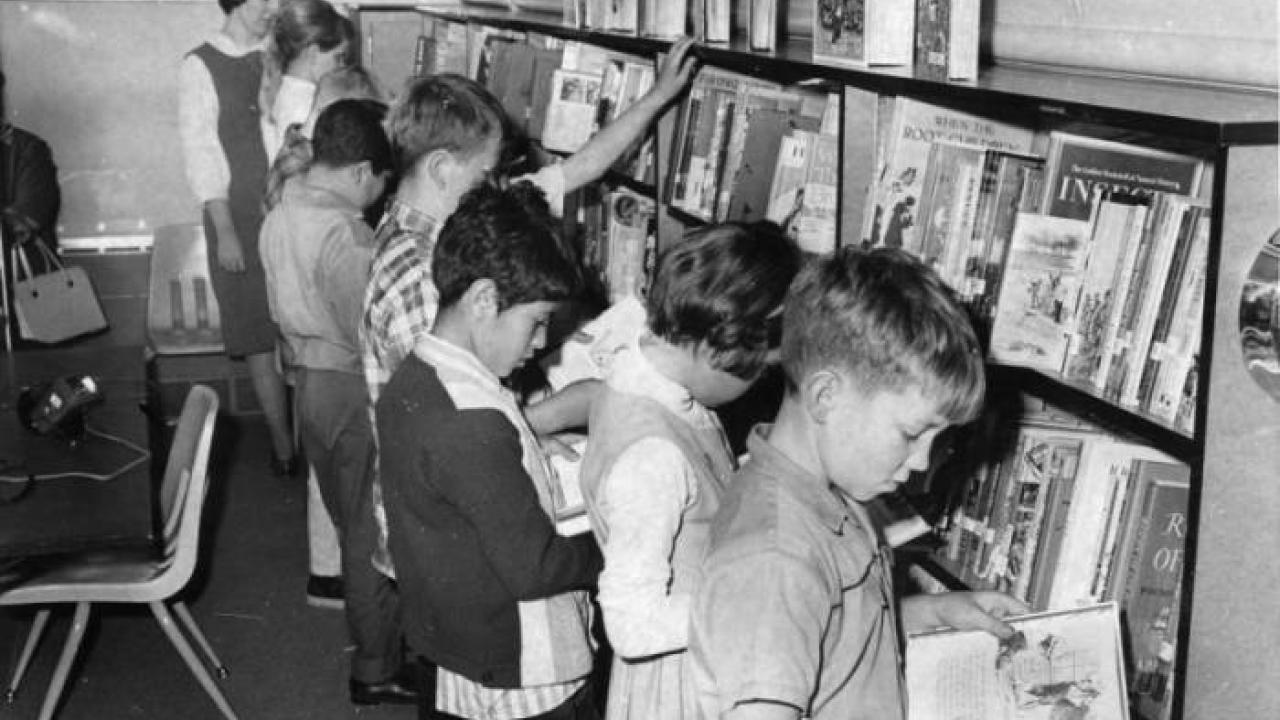 Children reading books inside a bookmobile, black and white photo