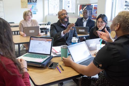 6 teachers discussing around computers