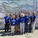 10 people in front of mural with blue shirts.