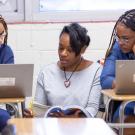 3 teachers talking with book and computers